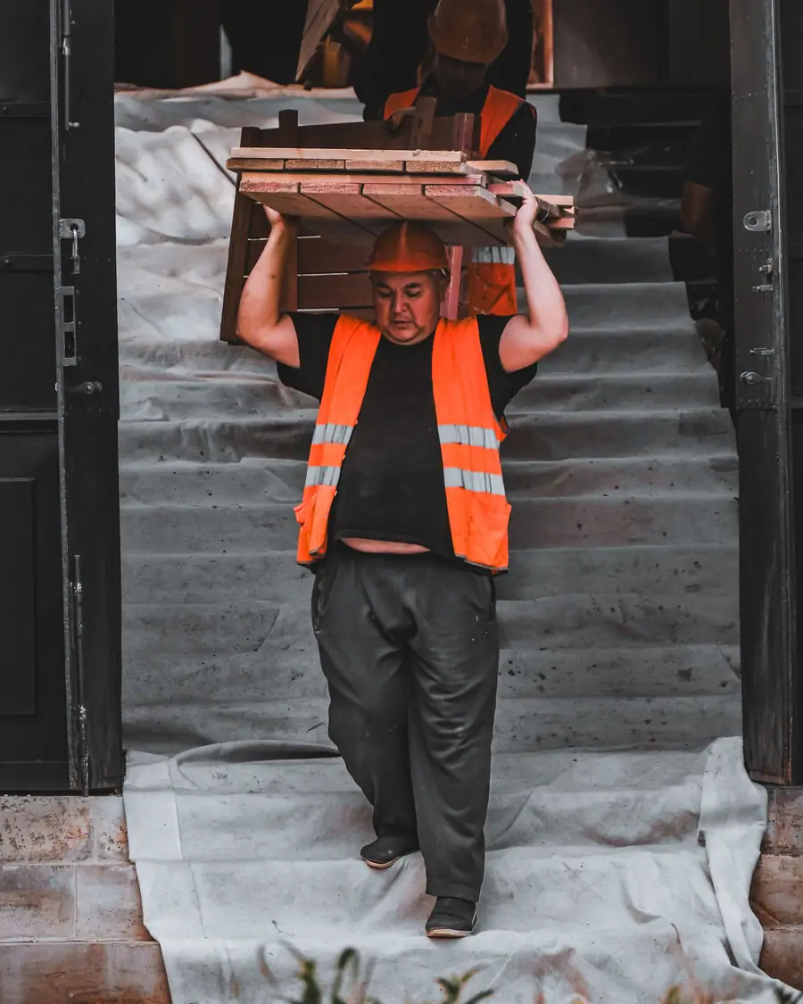Un trabajador sube una escalera cargando solo varias cajas